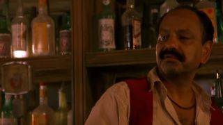 Cheech Marin standing in front of some bottles, looking annoyed in Desperado.