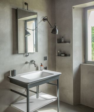 bathroom with gray walls, metal washstand, rectangular mirror and metal wall lamp