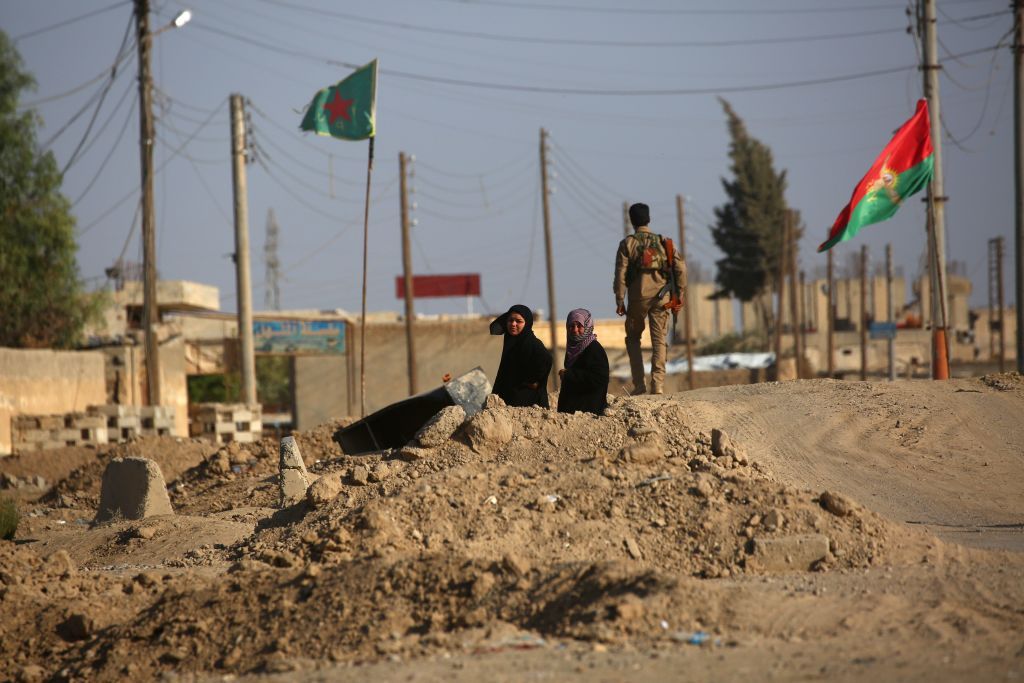 Syrian civilians wait at a checkpoint.