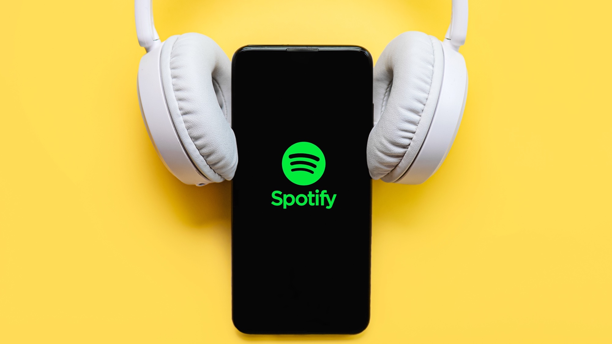 Spotify logo on a phone with white headphones resting on the phone