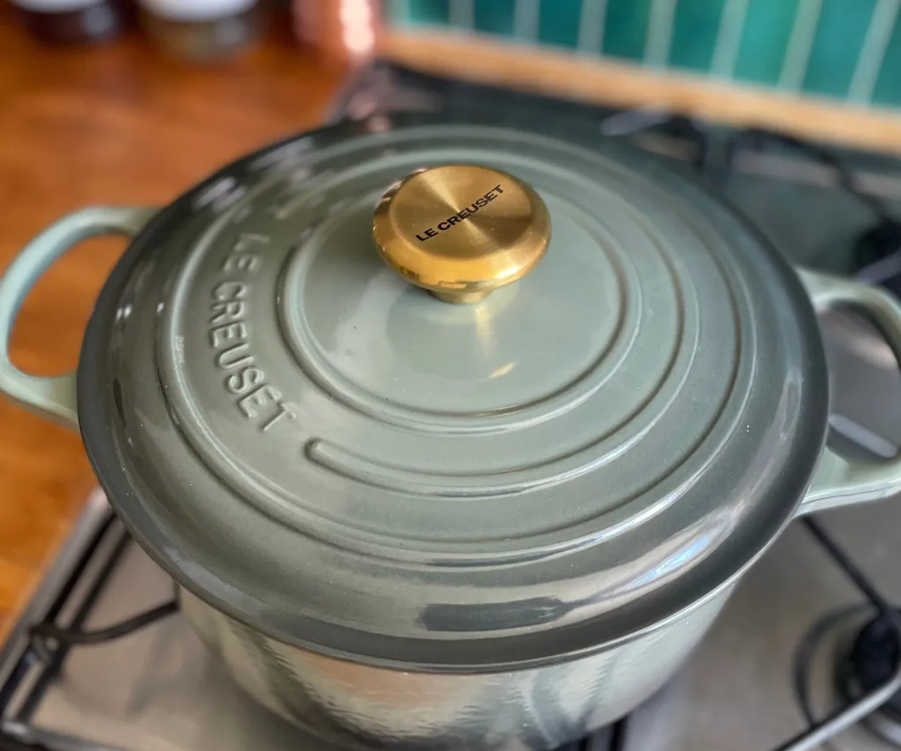 Le Creuset Dutch oven in the dusty green 'Thyme' colorway on a gas stove.