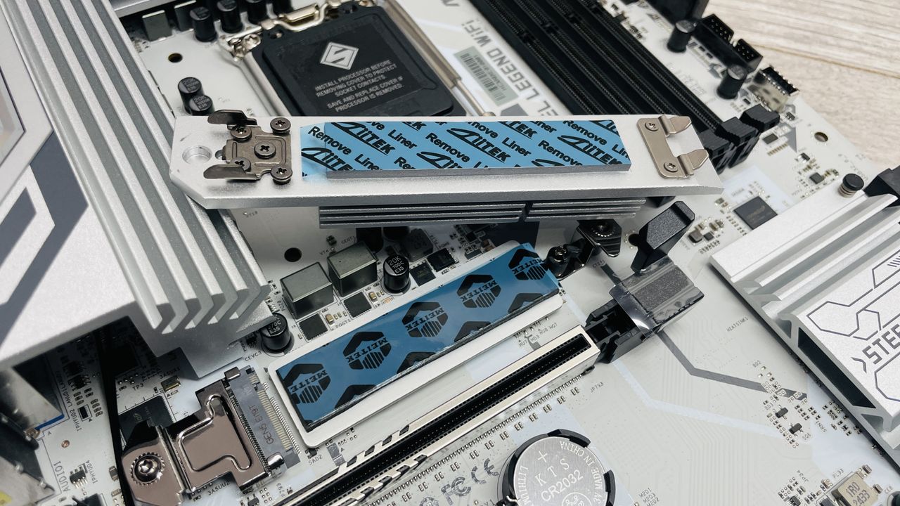 An ASRock B860 Steel Legend Wi-Fi motherboard on a desk with SSD covers removed.