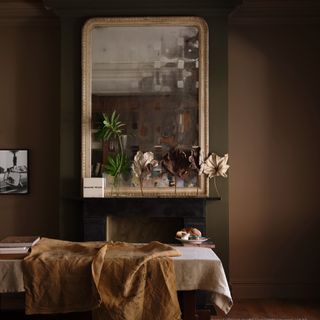 A dining room painted in Farrow & Ball's Broccoli Brown with the chimney breast in Reduced Green