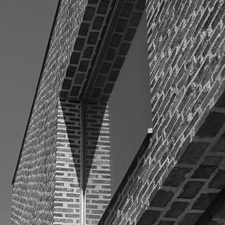 Building with exposed grey brick wall and glass panel