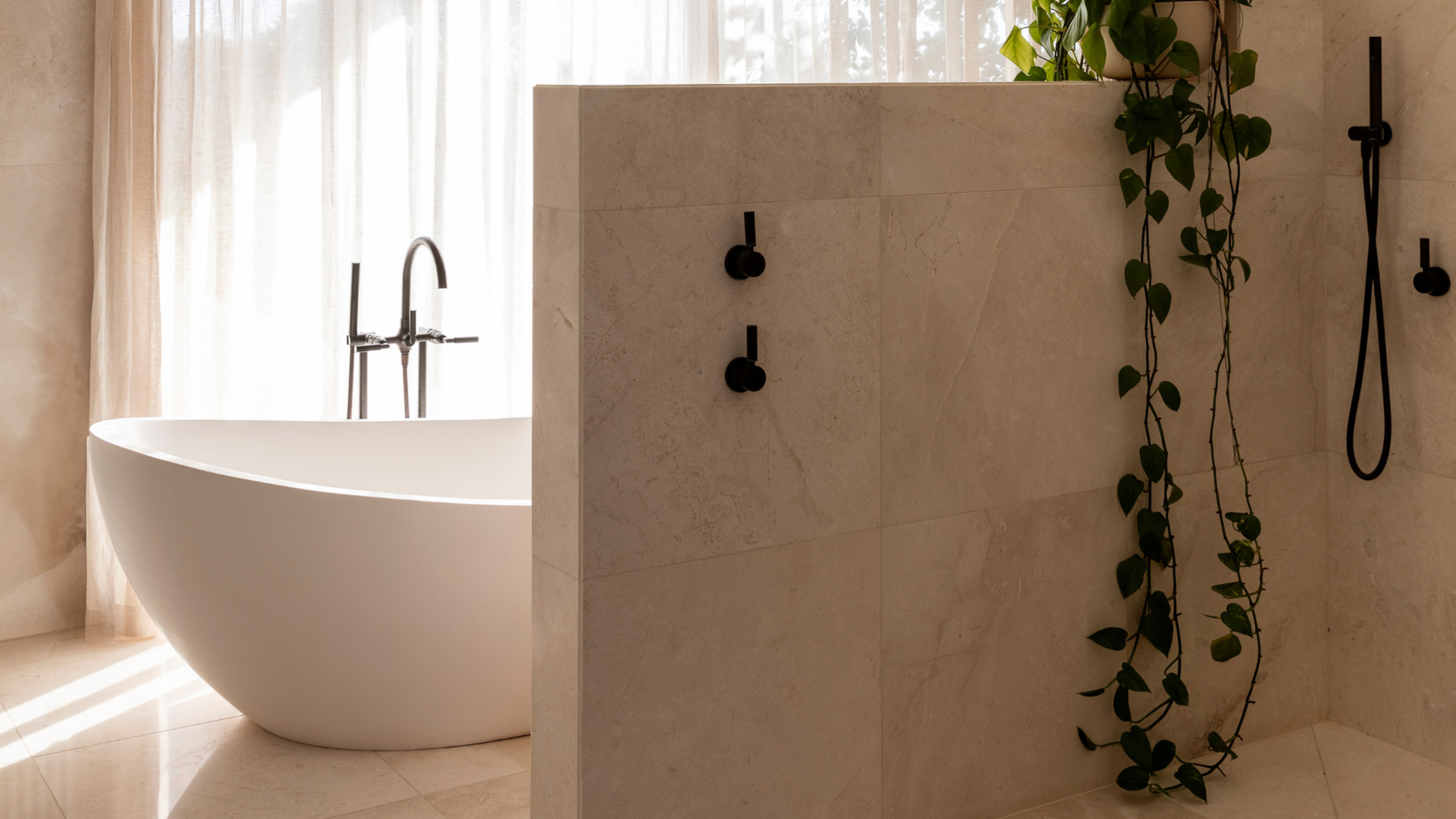 A minimalist stone bathroom, a shower space, a bath tub, and sheer window treatments