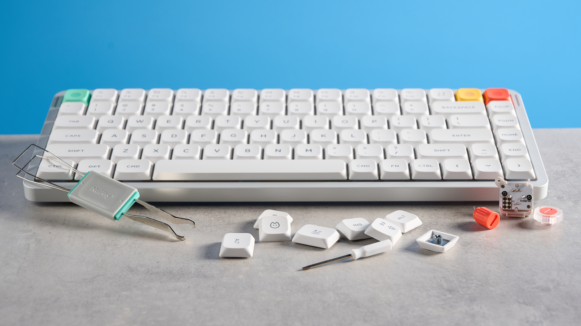 NuPhy Air75 V3 on a stone surface with accessories and spare keycaps