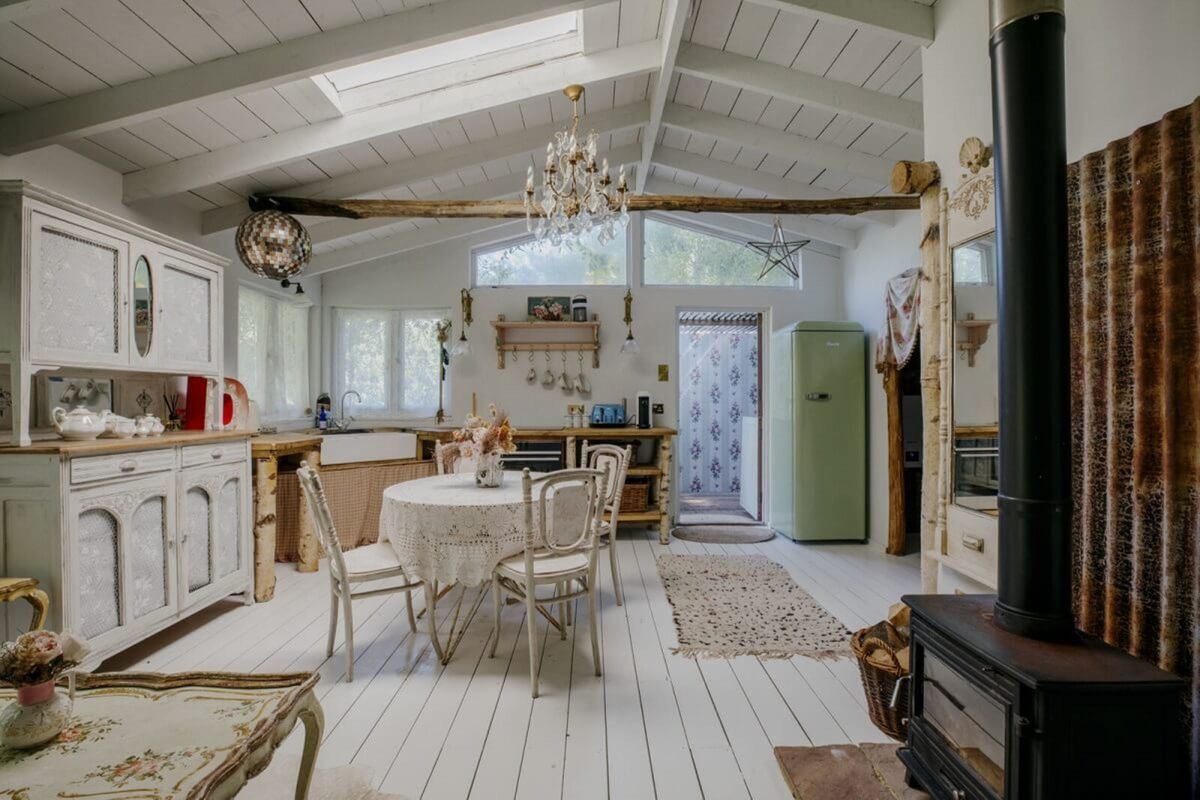 An open plan kitchen with living room has a wooden burner in the corner