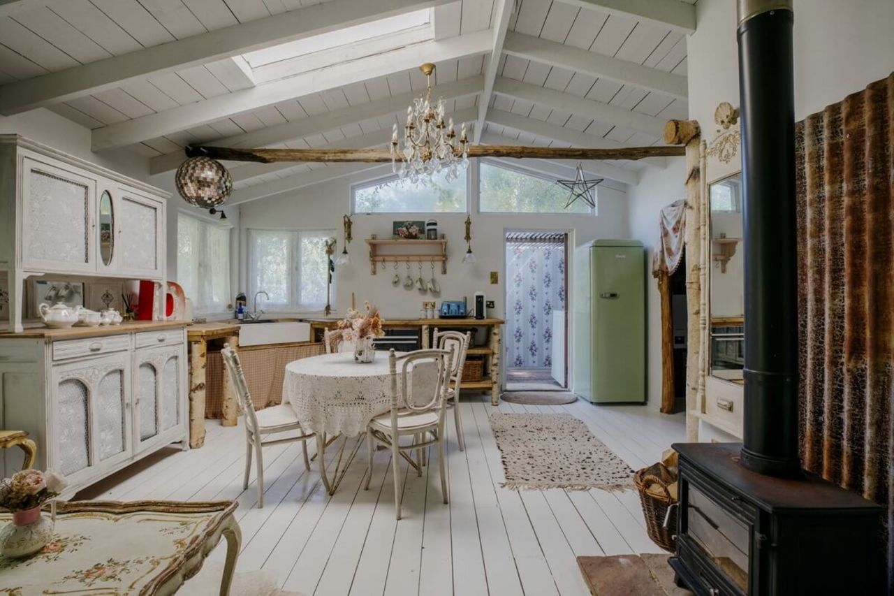 An open plan kitchen with living room has a wooden burner in the corner