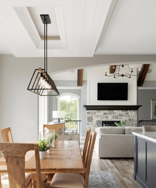 A modern white kitchen with an inverted tray ceiling and suspended lighting