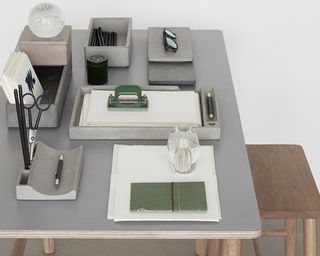 A grey desk with assortment of concrete desk organizer stationery and wooden chair