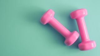 pink dumbbells on green backgroundfor strength training for women