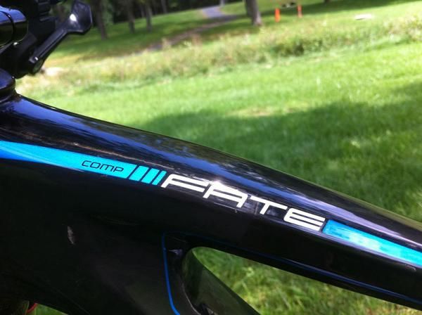 The Specialized Fate Comp comes in a carbon/blue color scheme. The bike has a glossy finish with white and blue highlights