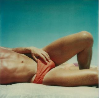 Man laying on the beach in red swimming trunks