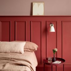 Red wall panelling and pink paint with a pink bed and red side table
