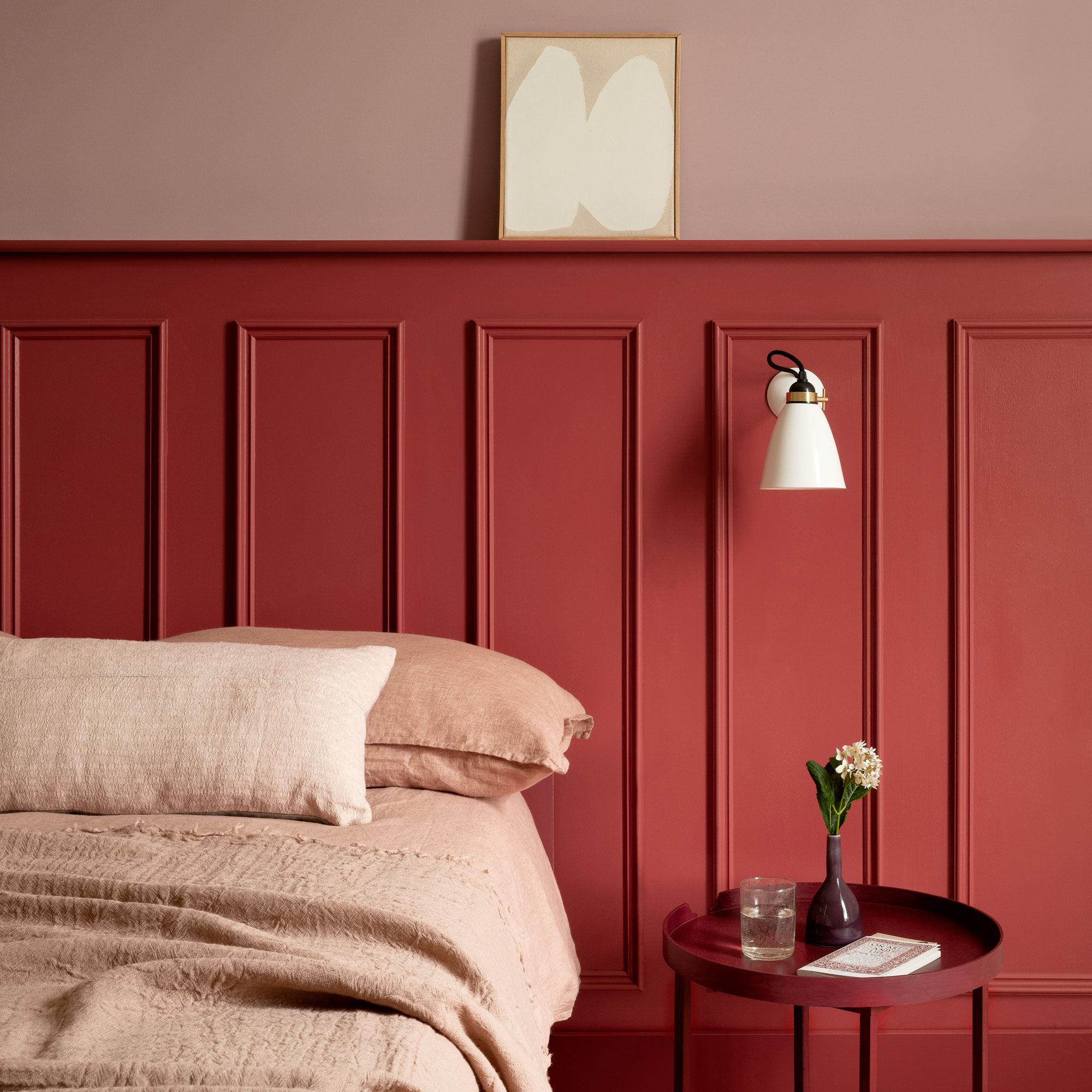 Red wall panelling and pink paint with a pink bed and red side table