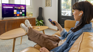 A woman relaxes with headphones in her ears, enjoying the headphone mode in the Roku TV fall software update