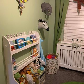 Green zoo themed nursery with white book shelf and soft toys