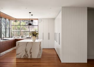 A kitchen with large windows sporting louvered blinds