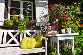 rustic garden ideas: bench in front of a cottage with fuchsias and window boxes