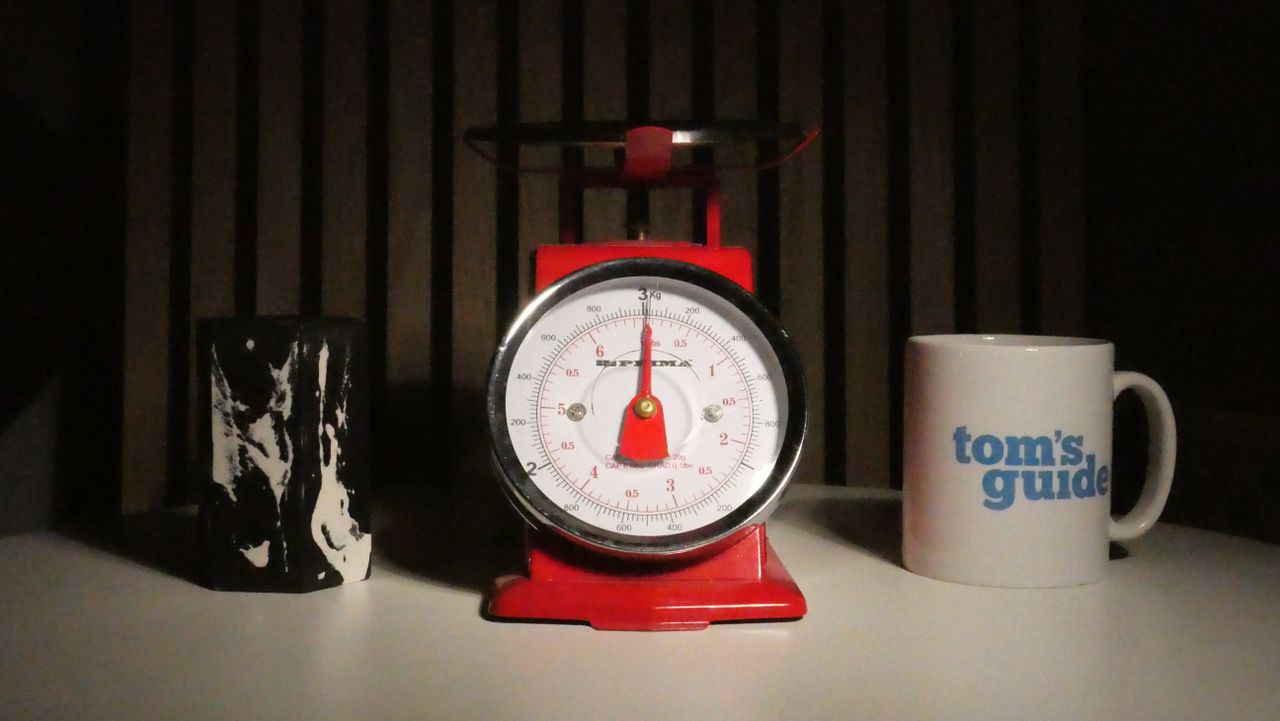 A photo of a set of red scales next to a Tom's Guide Mug.