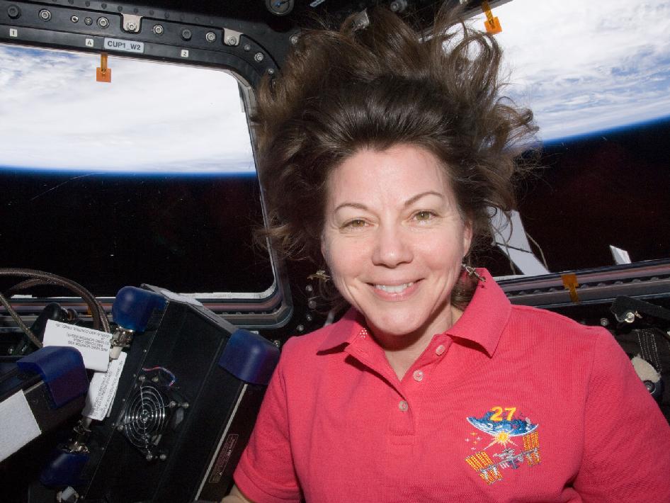 NASA astronaut Cady Coleman, Expedition 27 flight engineer, is pictured in the Cupola of the International Space Station. Earth’s horizon and the blackness of space are visible through the windows.