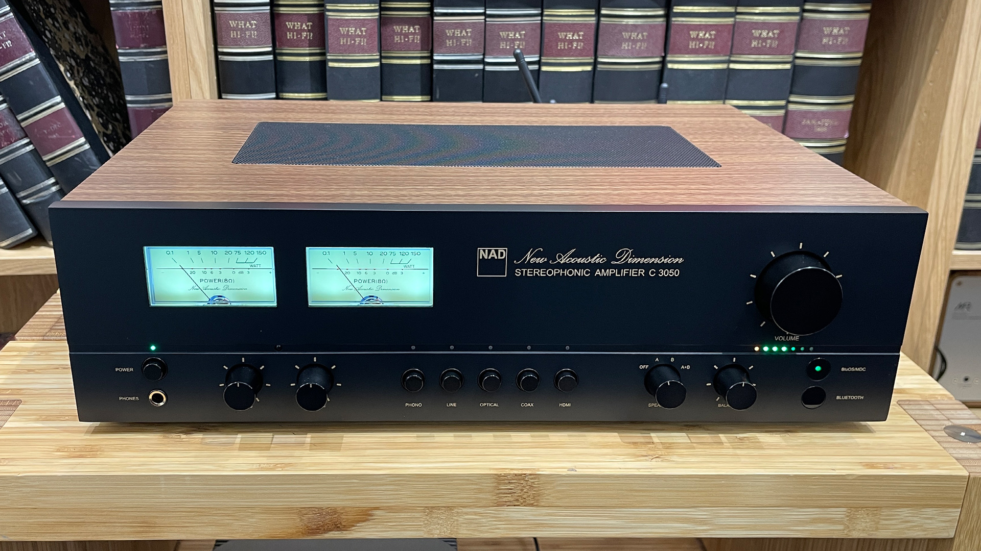 NAD C 3050 (with MDC2 BluOS-D module) streaming amplifier on wooden hi-fi rack in front of bookcase