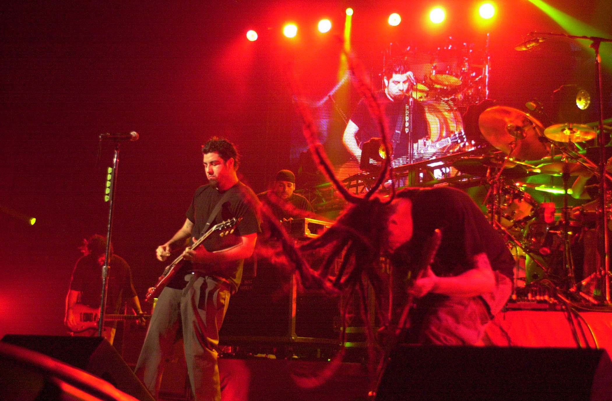 Deftones on stage playing, bathed in red light