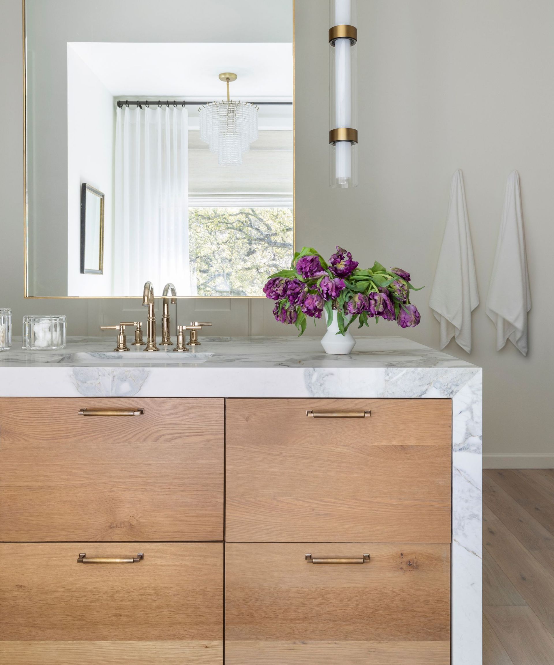 A wood and marble bathroom with a vanity island at the center