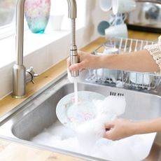 Woman washing dishes in a kitchen sink