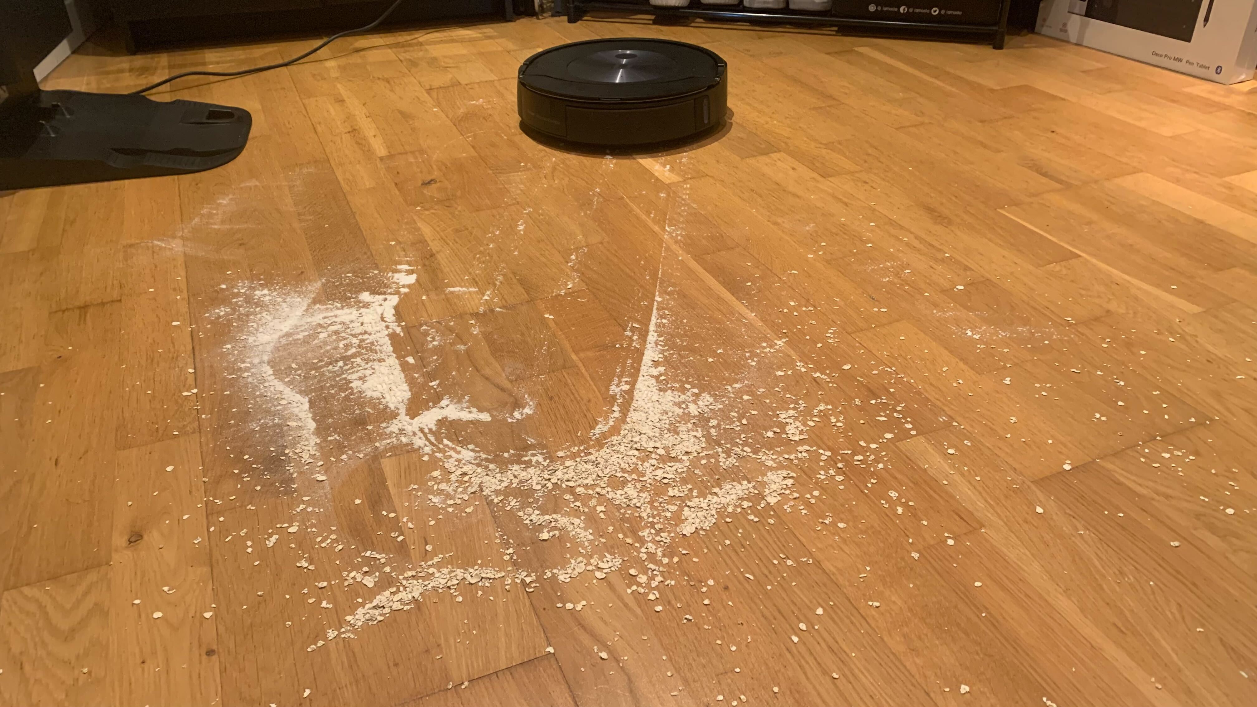 The floor with scattered oats and flour during the iRobot Roomba Combo j7+'s clean up of a heavy spill