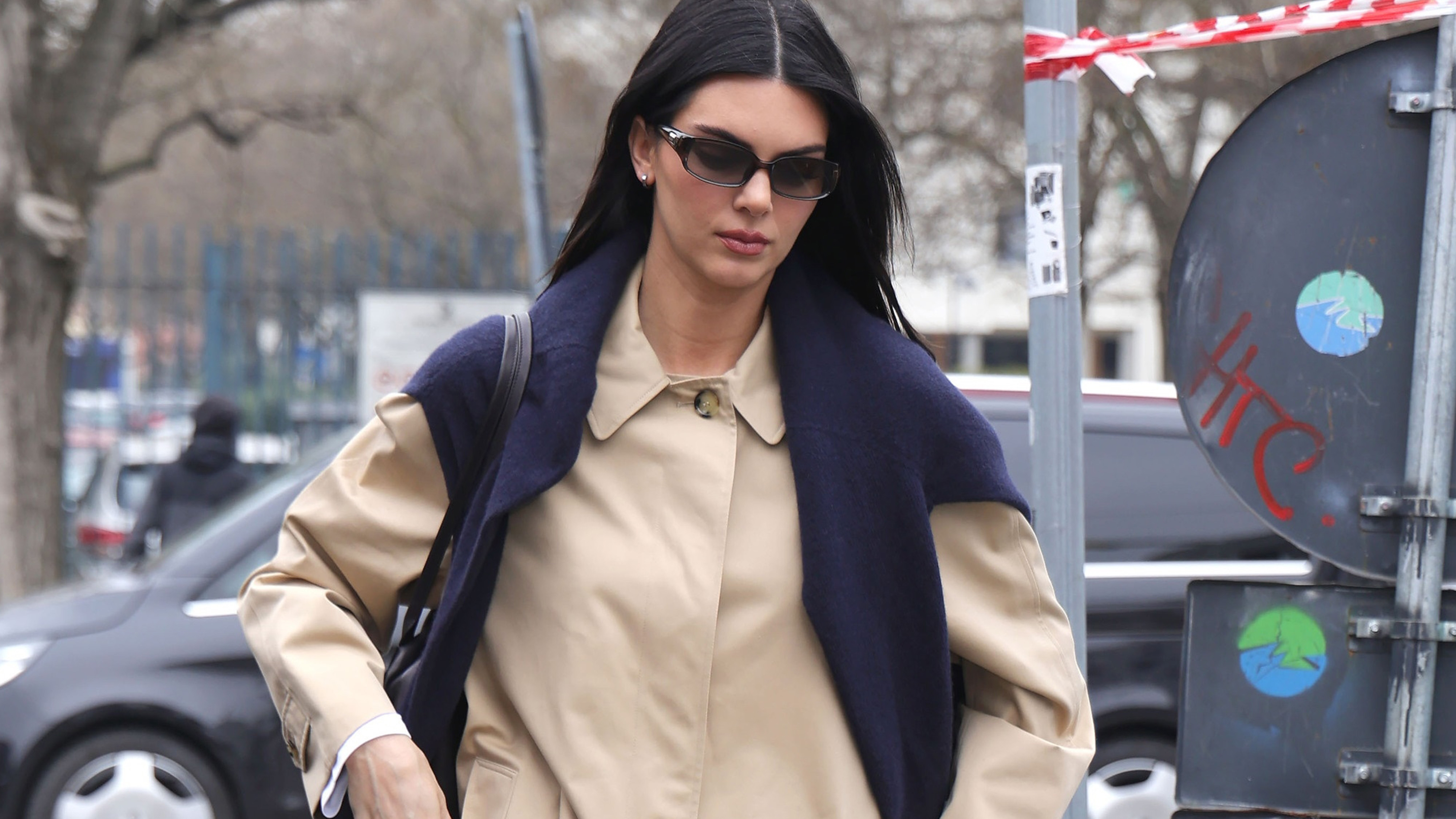Kendall Jenner seen out in Milan during Milan Fashion Week 2026. The supermodel stepped out in the city wearing a black The Row bag, a khaki trench coat, white pants, and black high-vamp pumps from Phoebe Philo.