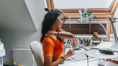 Woman struggling with back pain and bad posture at desk