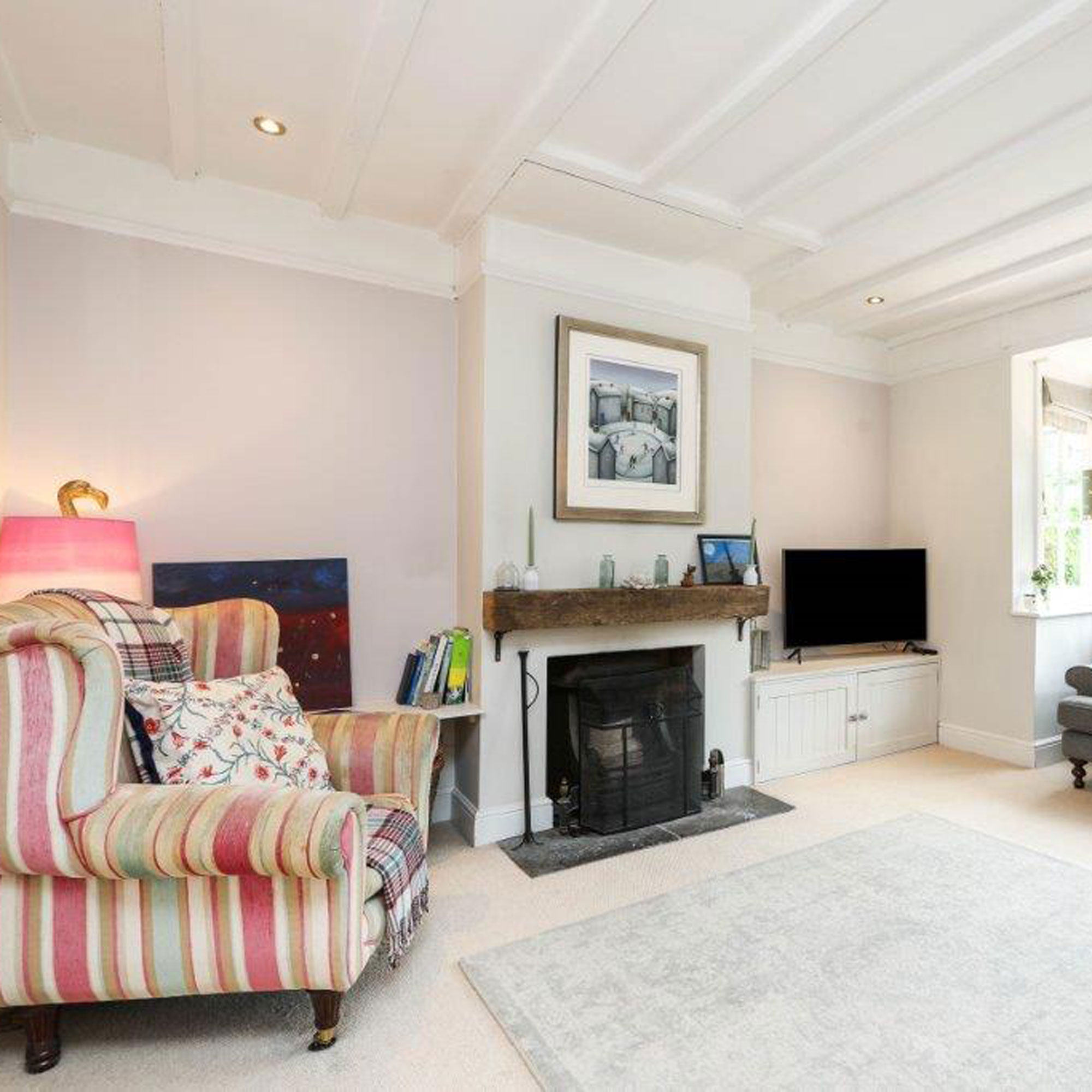 living room with pink stripey chair and fireplace with oak mantle