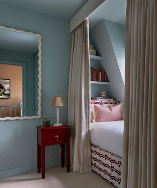 blue color drenched bedroom with a built-in bed nook and pops of red