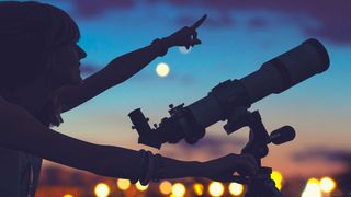 Woman looking over city with telescope at night