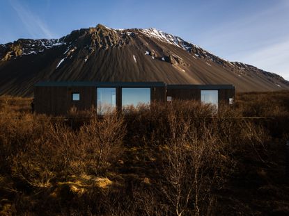 Wooden cabin in front of a snow-capped mountain