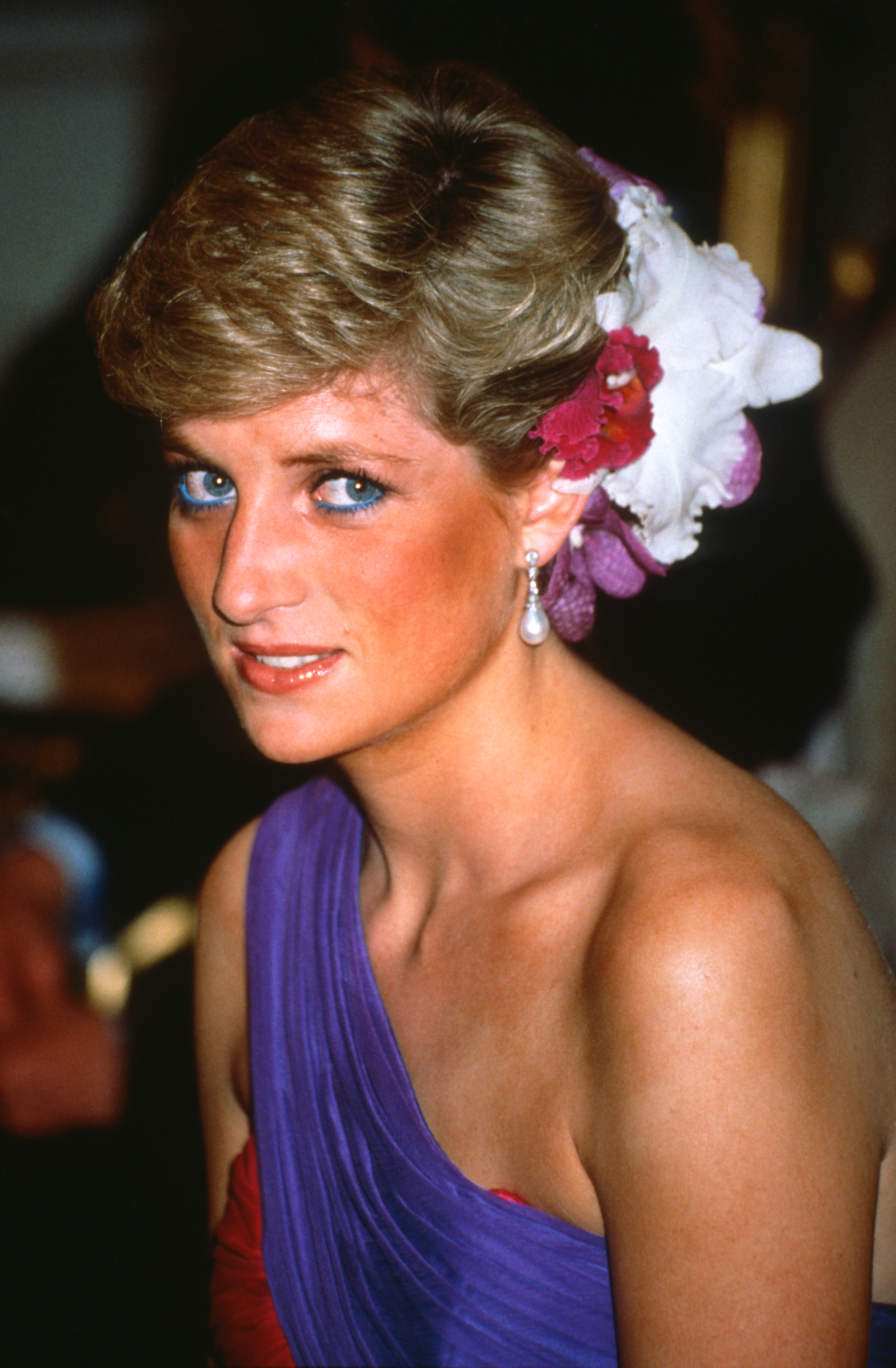 Princess Diana wearing flowers in her hair and a red and purple dress