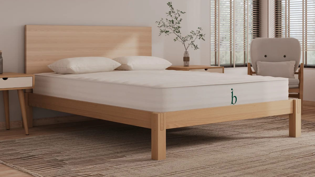 The Birch Essential Mattress on a bed frame in a room 