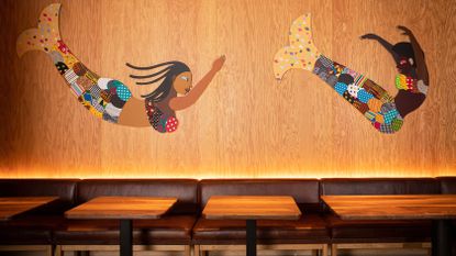 Artwork Black mermaids by Derrick Adams on wooden wall at Hav & Mar restaurant in New York