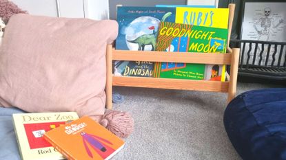 Bedtime stories piled in a small book shelf with comfy pink cushions around it