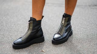 A guest wears black shiny leather zipper ankle boots, outside Gestuz, during Copenhagen Fashion Week Spring/Summer 2023, on August 09, 2022 in Copenhagen, Denmark.