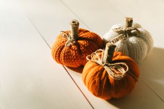Decorative knitted pumpkins in cream, orange and dark orange, tied with string.