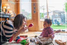 Nanny sitting on the floor shaking maracas to entertain an infant