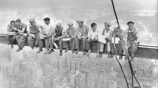 A black and white image of 11 workers sitting on an iron girder high above New York, during the building of the Rockefeller Center