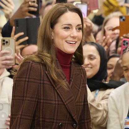 Princess Kate in front of a crowd in London wearing a plaid coat with an asprey bag