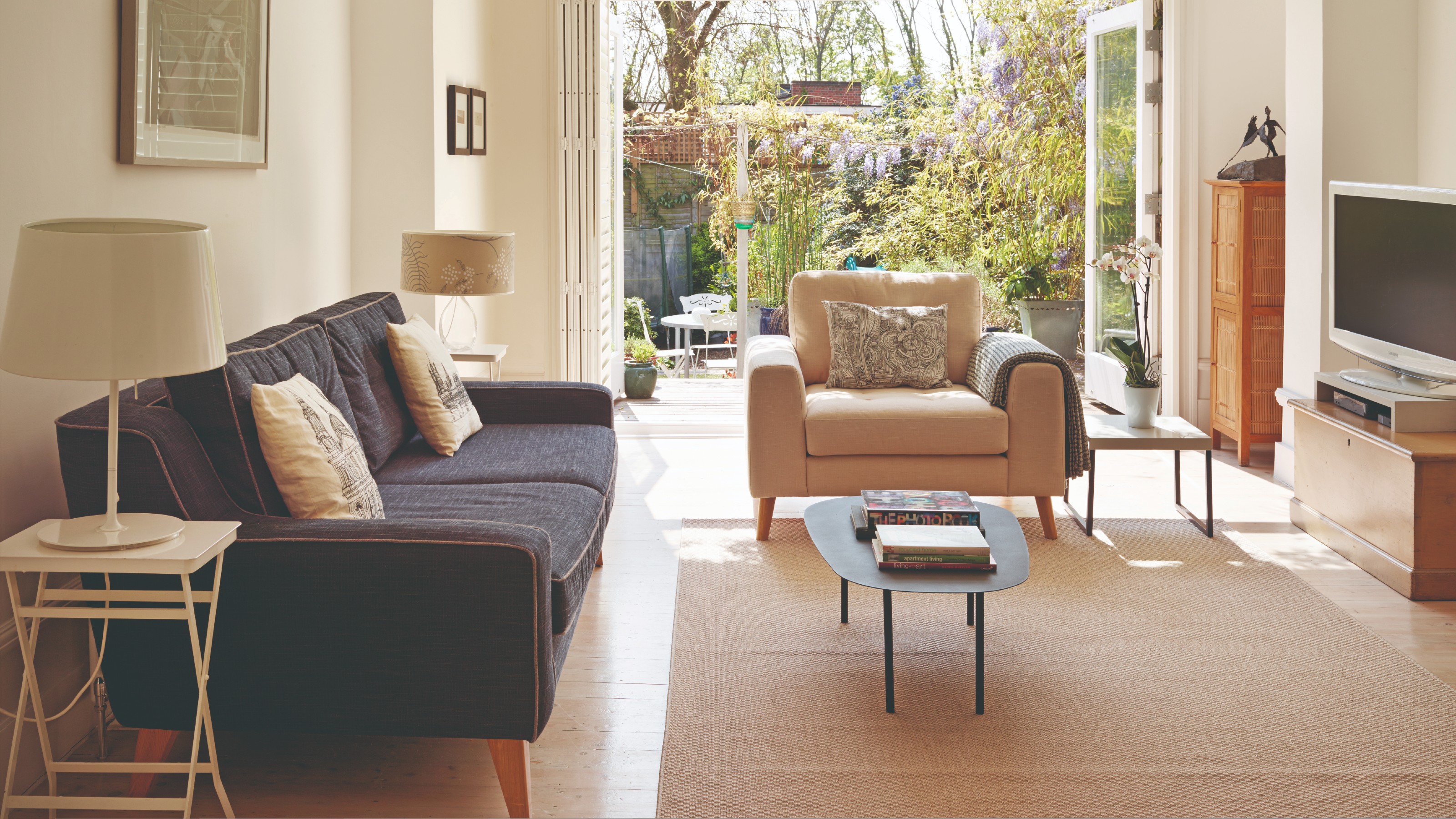 A living room with a beige rug, a dark sofa and a beige armchair