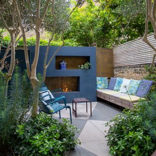 garden with blue painted wall and fireplace bench seating with cushions