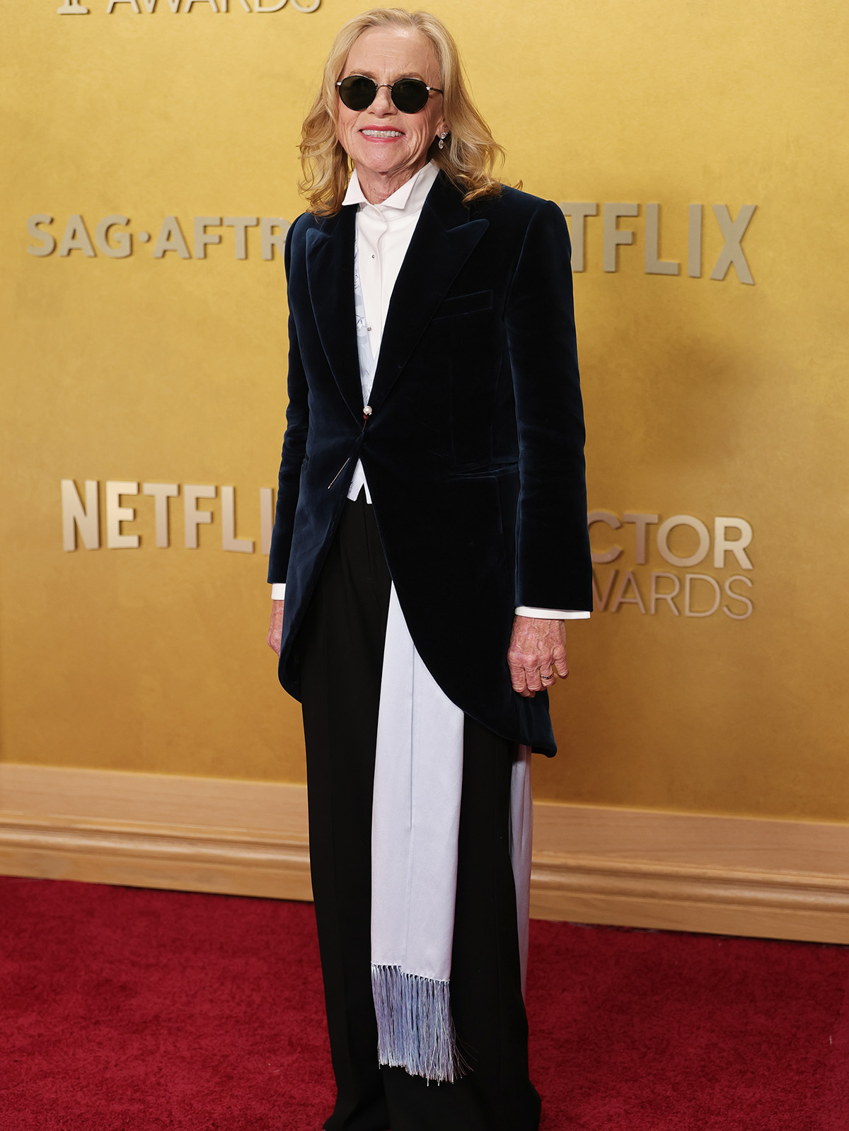 Amy wears a blazer with a white top, and black pants.