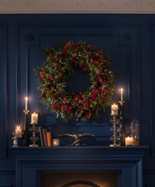 Dramatic fireplace scene with seasonal wreath and candlelight