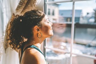 A woman looking out the window at the sunshine